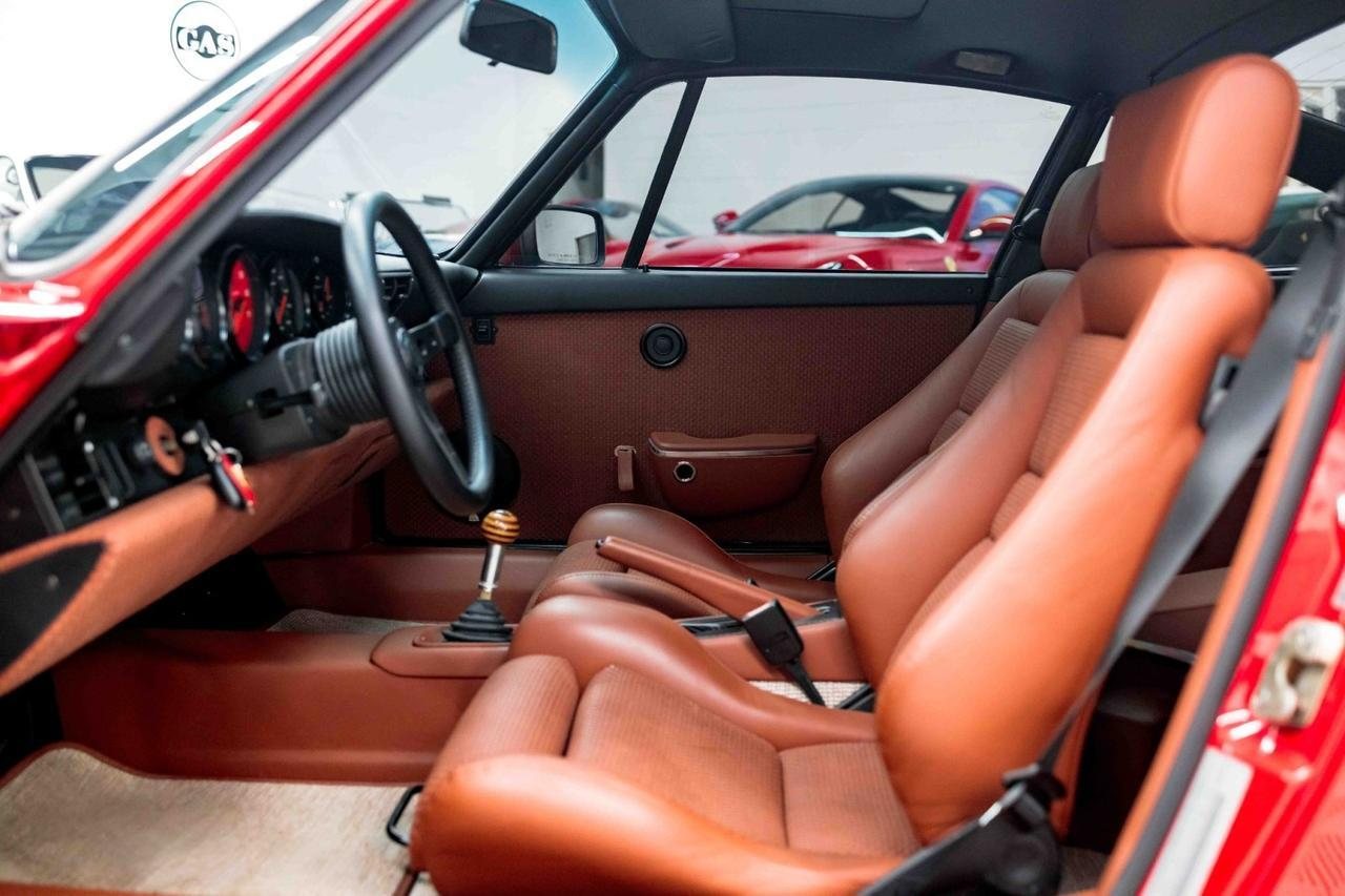 964 interior from the driver door: Bourbon leather Recaro seats, woven door cards, black dash, laminated wood shift knob