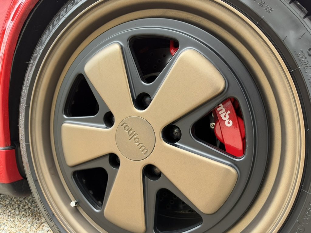 Bronze Rotiform five-spoke forged wheel with red Brembo caliper and drilled disc behind it